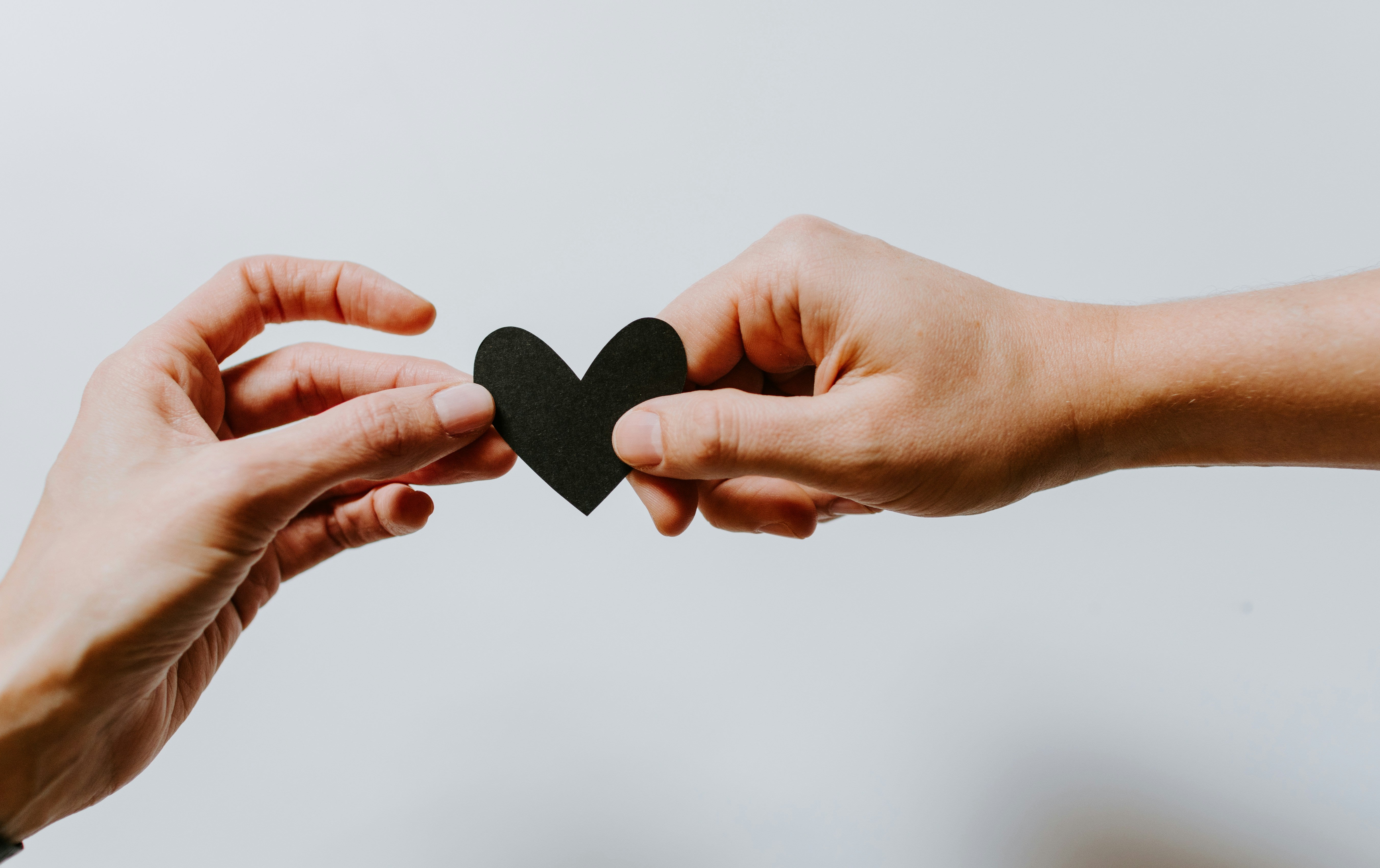 Two hands holding a paper heart.Photo by Kelly Sikkema on Unsplash